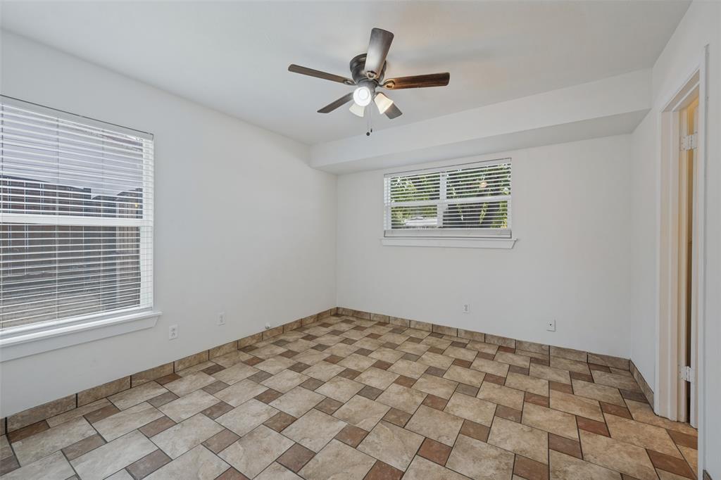 3584 Regal Road Fort Worth, TX 76111 - Photo 7 of 12 Neutral wall finishes, patterned tile flooring, a ceiling fan with integrated lighting, and multiple windows with blinds