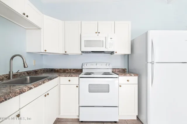 a view of a kitchen with sink and refrigerator