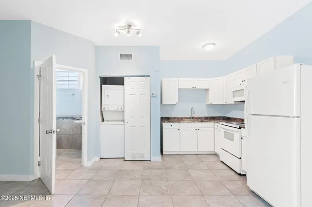 a kitchen with white cabinets and refrigerator