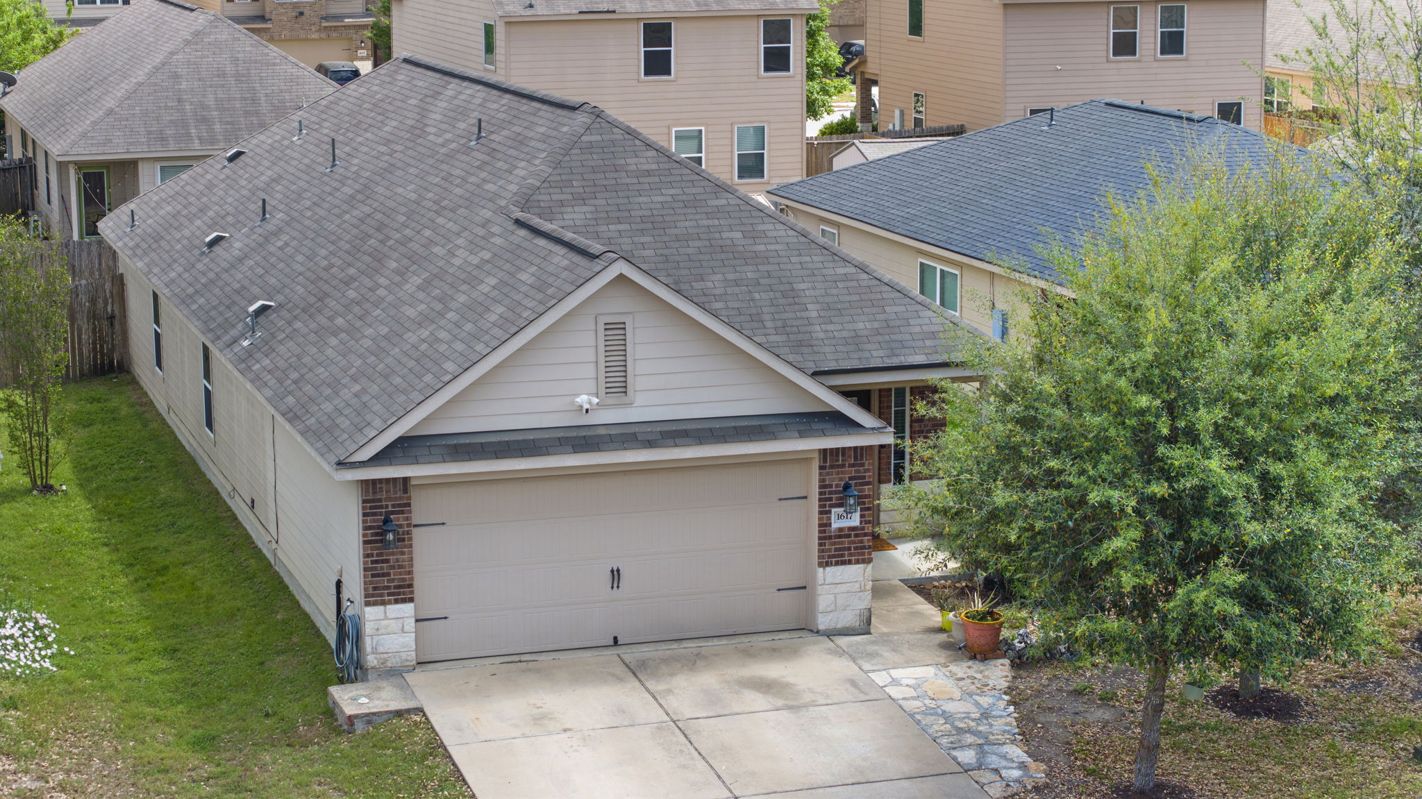 1617 Treeta Trail Kyle, TX 78640 - Photo 11 of 39 View of front facade featuring roof with shingles, brick siding, driveway, a front lawn, and a residential view