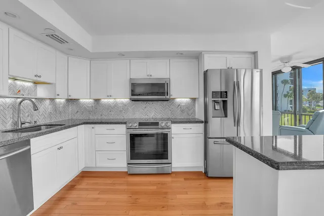 a kitchen with stainless steel appliances granite countertop a stove a sink and a refrigerator