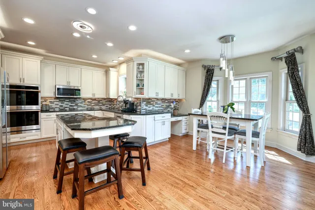 a kitchen with kitchen island a large counter top space appliances and a large window