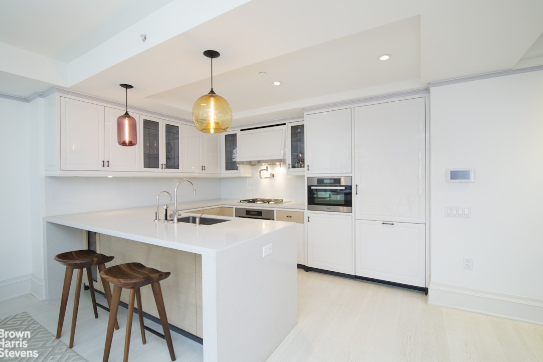 21 East 61st Street, Unit 3C Manhattan, NY 10065 - Photo 2 of 6 a kitchen with stainless steel appliances granite countertop a sink a stove a refrigerator and white cabinets