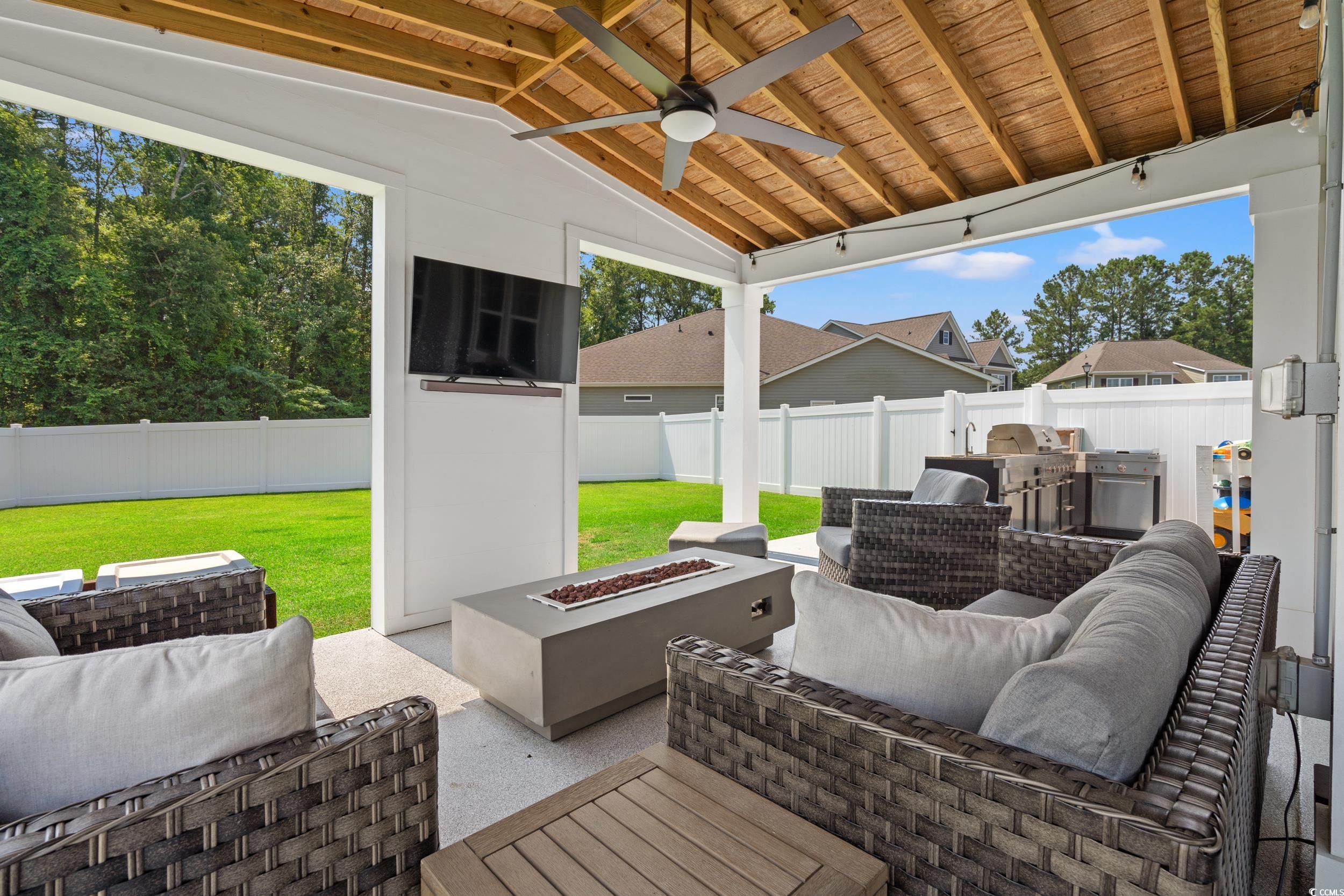 405 Spring View Little River, SC 29566 - Photo 2 of 40 Fenced backyard with an outdoor living space with a fire pit, ceiling fan, and a patio area