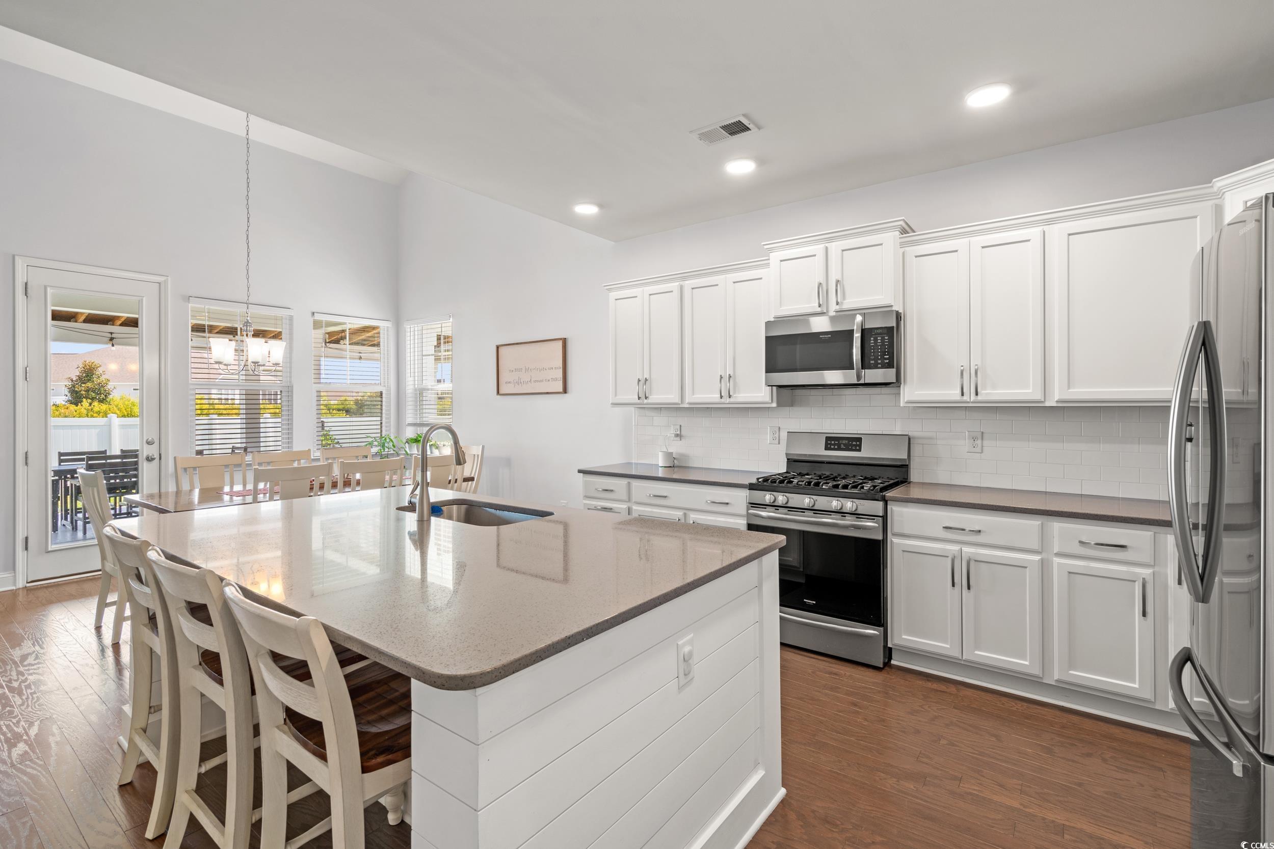 405 Spring View Little River, SC 29566 - Photo 3 of 40 Kitchen with stainless steel appliances, dark wood-style flooring, a chandelier, decorative backsplash, and white cabinets