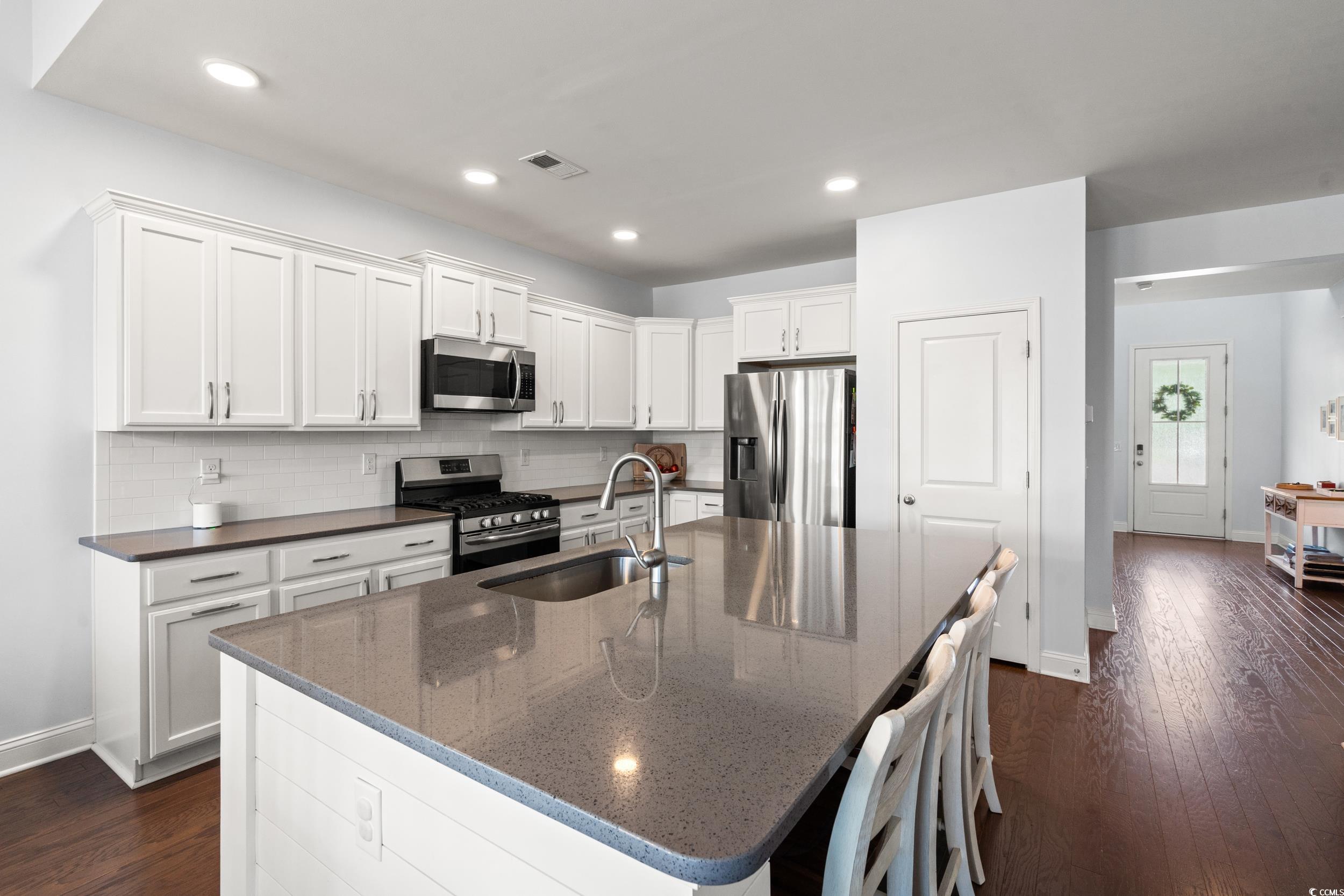 405 Spring View Little River, SC 29566 - Photo 4 of 40 Kitchen featuring appliances with stainless steel finishes, backsplash, dark wood-type flooring, white cabinets, and recessed lighting