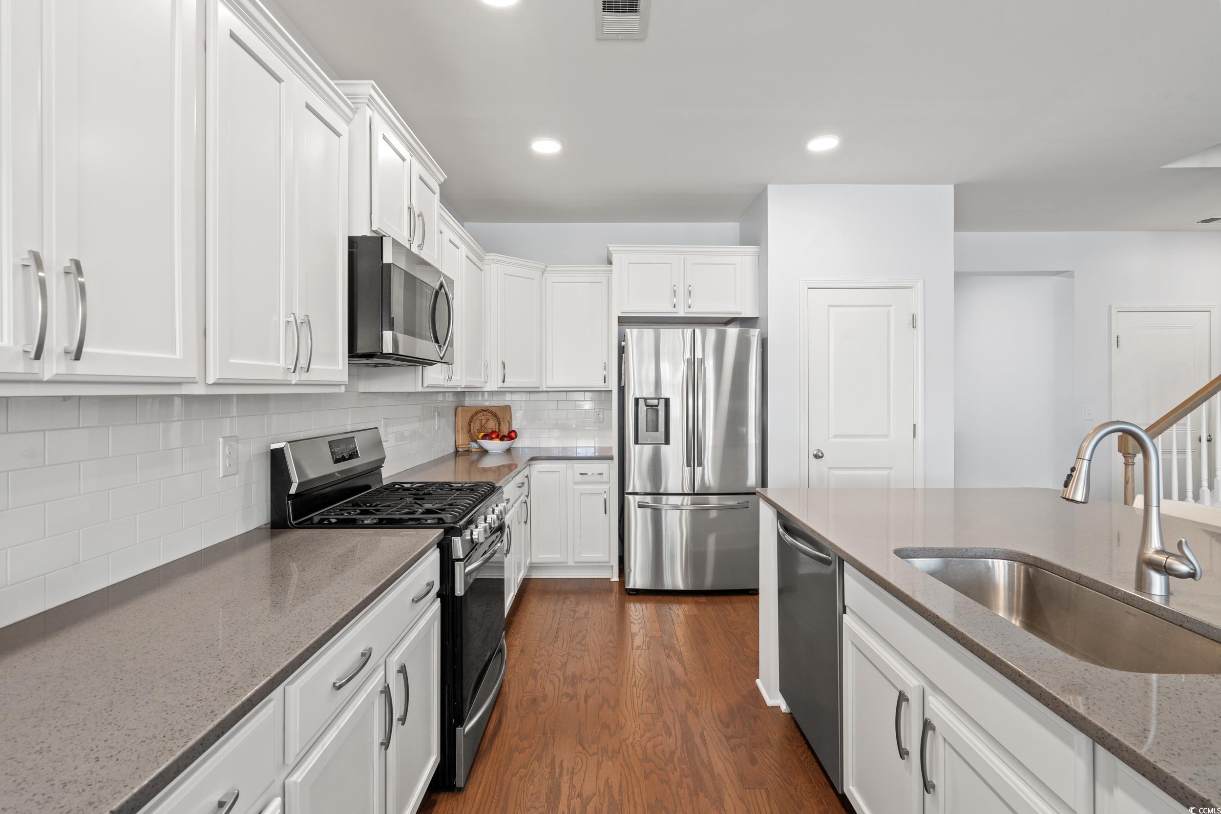 405 Spring View Little River, SC 29566 - Photo 5 of 40 Kitchen featuring stainless steel appliances, white cabinets, light stone countertops, dark wood finished floors, and decorative backsplash