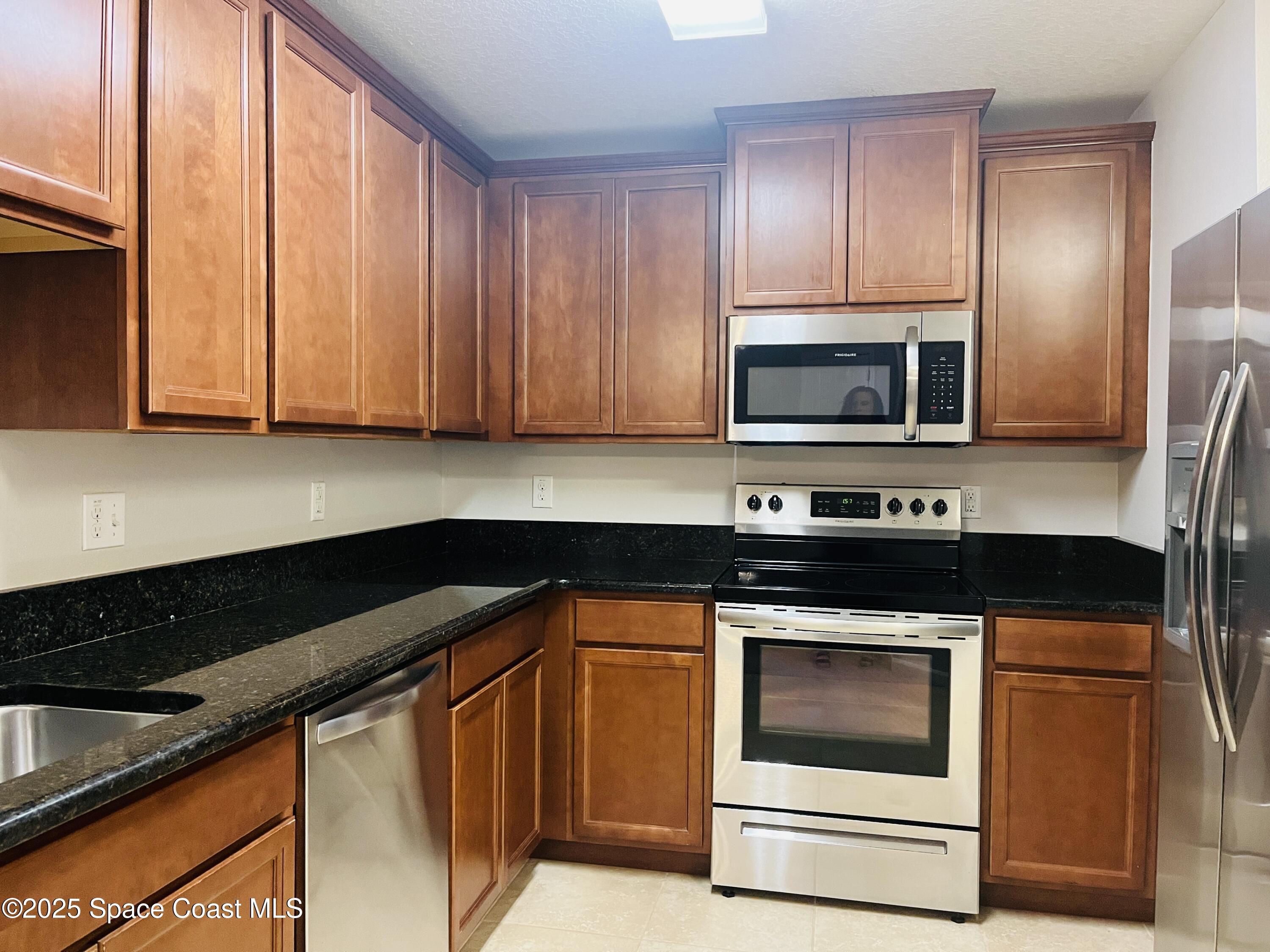 4017 Meander Place, Unit 103 Rockledge, FL 32955 - Photo 3 of 10 a kitchen with granite countertop wooden cabinets and stainless steel appliances