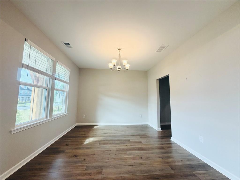 607 Michigan Circle Hoschton, GA 30548 - Photo 23 of 27 an empty room with wooden floor chandelier and windows