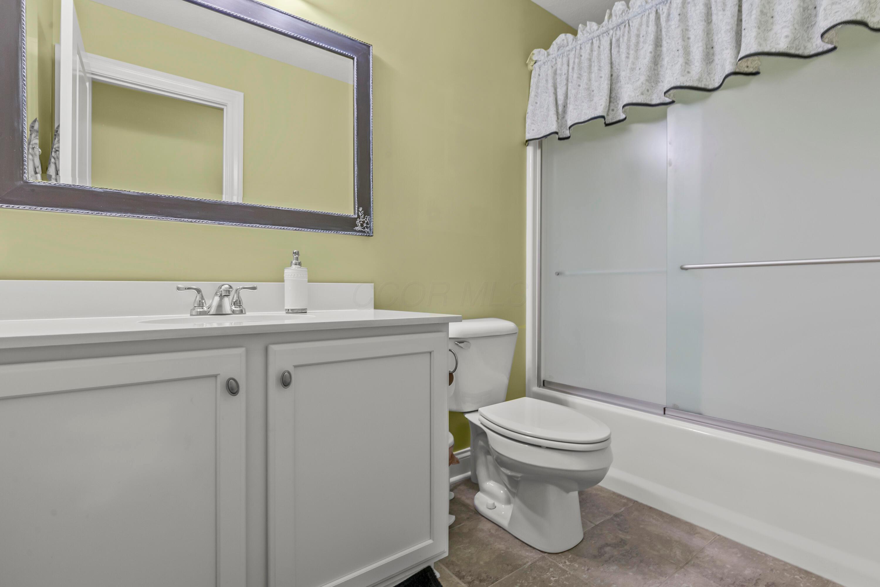 3582 Panhandle Road Delaware, OH 43015 - Photo 18 of 65 • Ceramic tile flooring • Sage painted walls • Enclosed vanity with quartz countertop • 3 bulb wall light • Mirror is negotiable • Wall cabinet does not remain • Tub/shower combination with glass doors