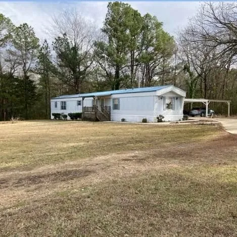 a view of a house with yard and trees in the background