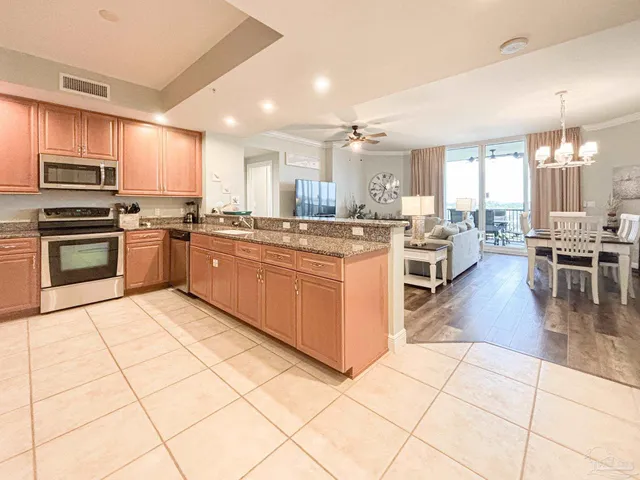 a kitchen with stainless steel appliances granite countertop a stove top oven a sink dishwasher and white cabinets next to a window