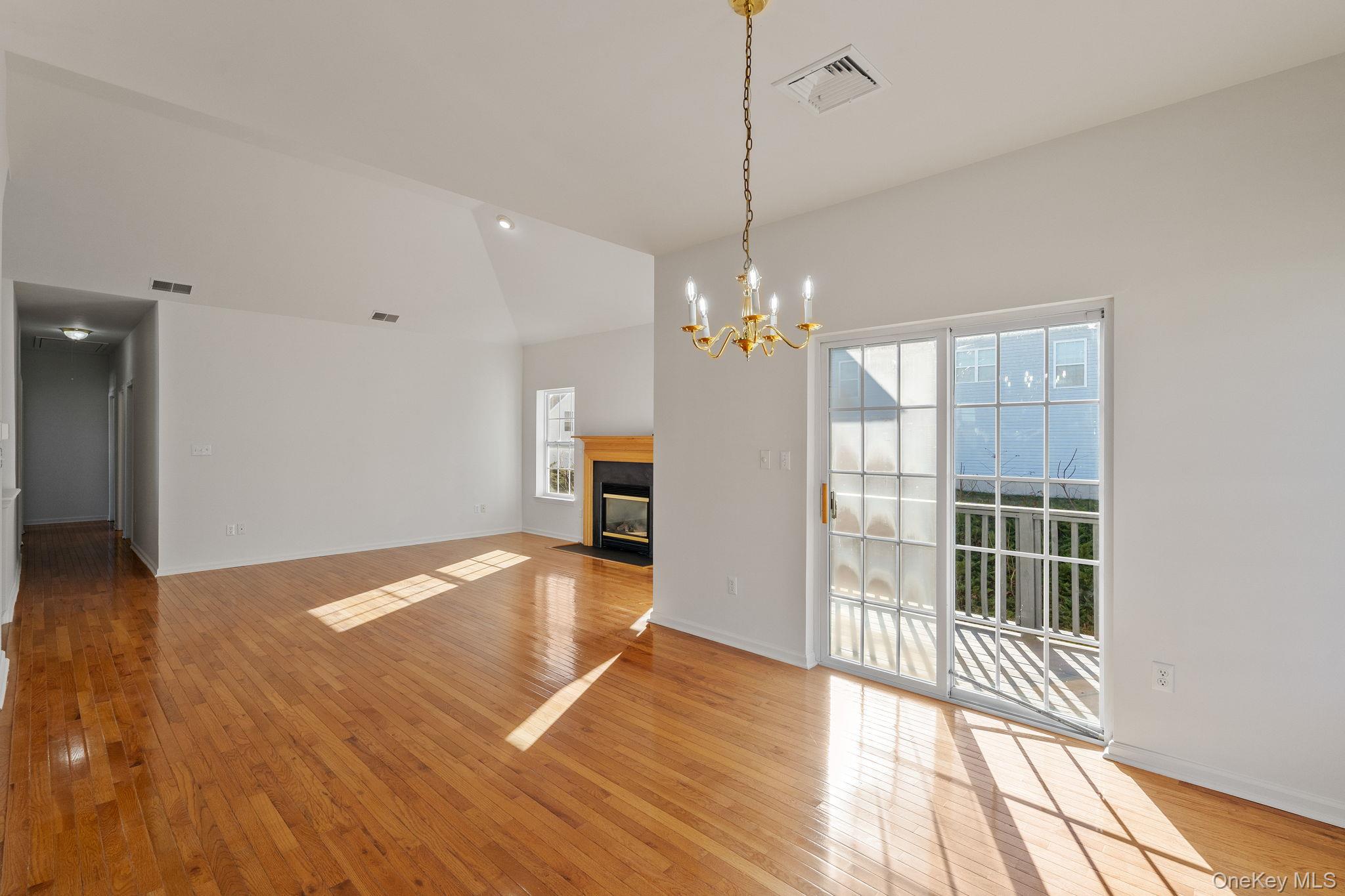 17 Carmella Road Highland, NY 12528 - Photo 13 of 48 Unfurnished dining area with light wood-type flooring, a chandelier, lofted ceiling, and a fireplace with flush hearth