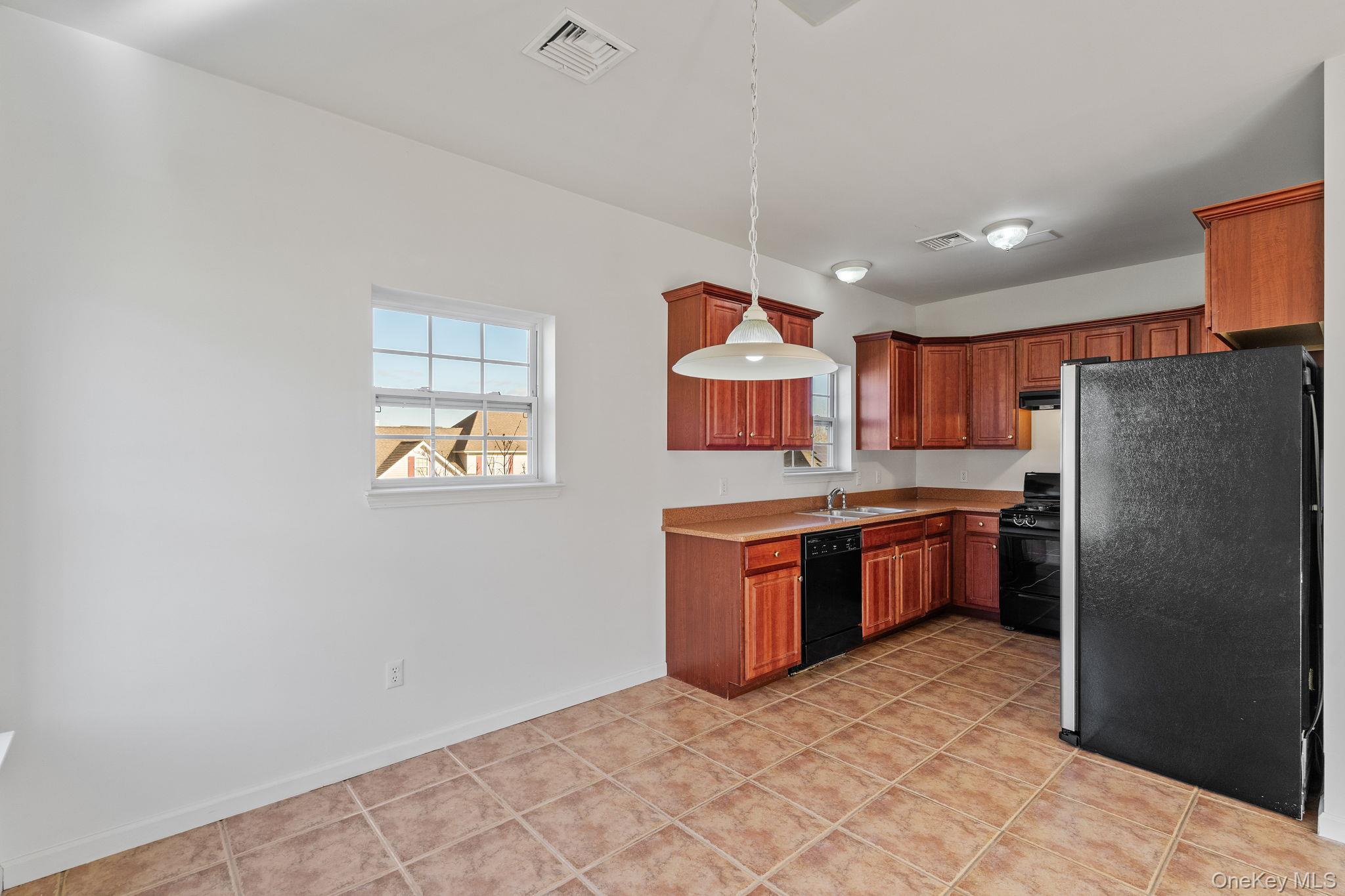 17 Carmella Road Highland, NY 12528 - Photo 14 of 48 Kitchen featuring black appliances, hanging light fixtures, light countertops, light tile patterned floors, and brown cabinets