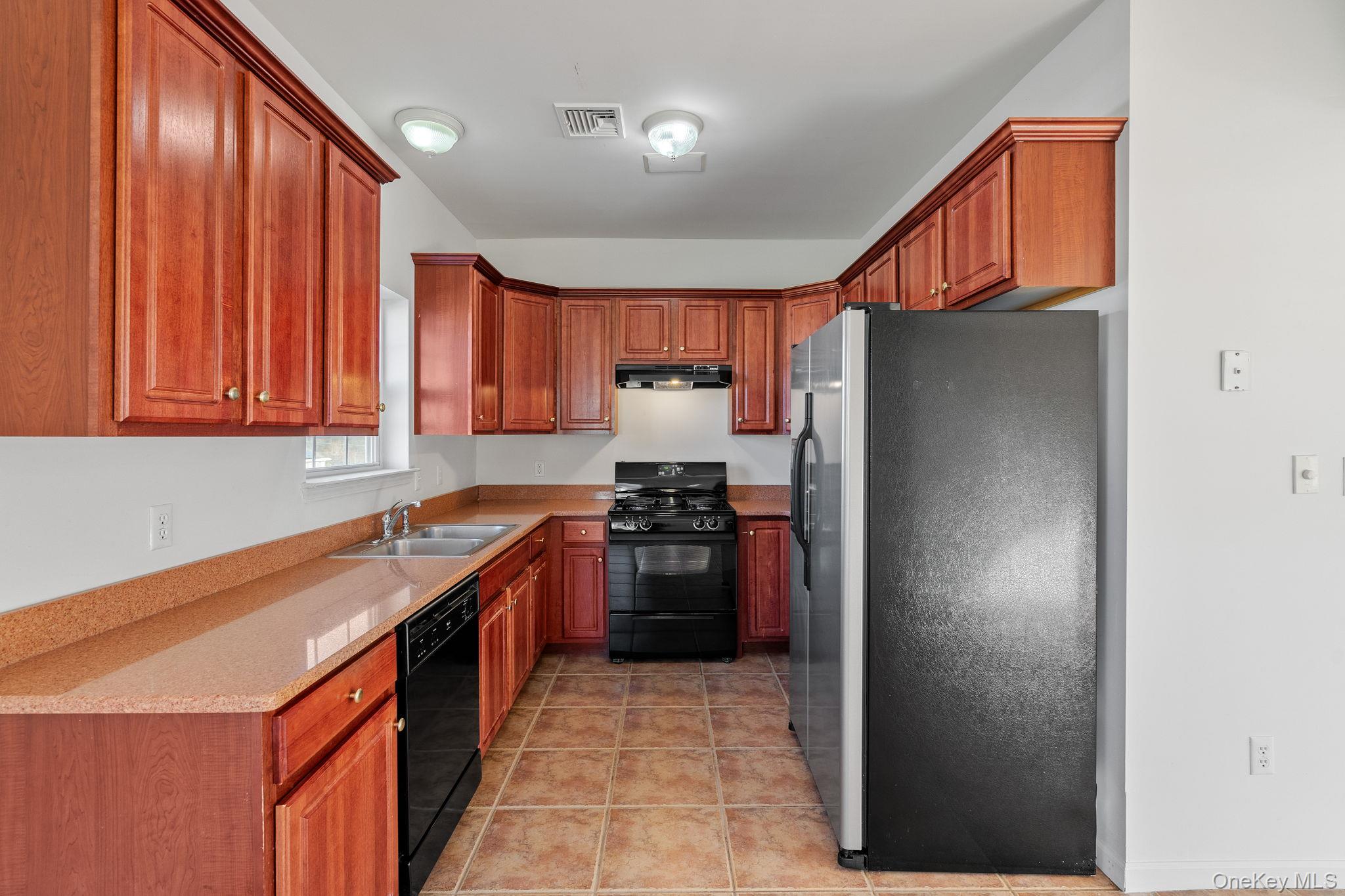 17 Carmella Road Highland, NY 12528 - Photo 16 of 48 Kitchen featuring black appliances, light tile patterned floors, under cabinet range hood, brown cabinetry, and light stone counters