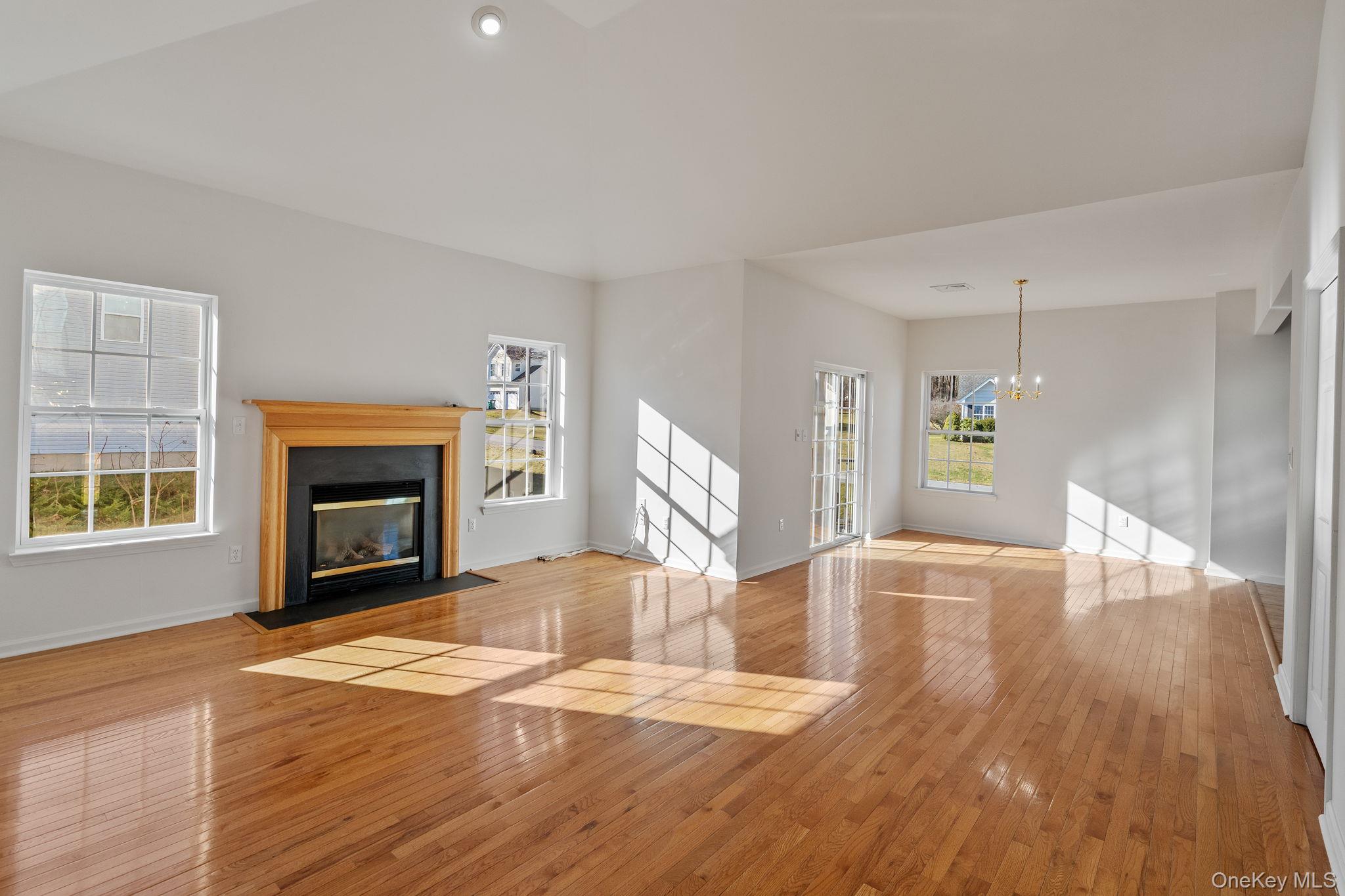 17 Carmella Road Highland, NY 12528 - Photo 7 of 48 Unfurnished living room featuring a fireplace with flush hearth, light wood-style flooring, and a chandelier