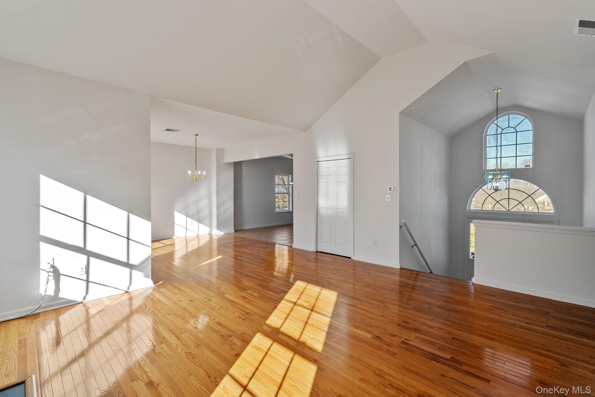 17 Carmella Road Highland, NY 12528 - Photo 8 of 48 Unfurnished living room featuring a chandelier, light wood finished floors, high vaulted ceiling, and healthy amount of natural light