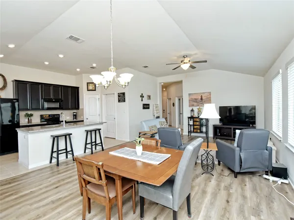 a kitchen with kitchen island granite countertop a stove a sink a refrigerator with a dining table and chairs