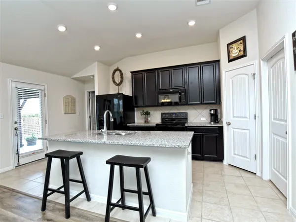 a kitchen with granite countertop a table chairs stove and refrigerator