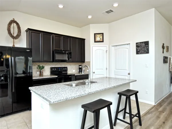 a kitchen with granite countertop kitchen island stainless steel appliances a sink stove and refrigerator