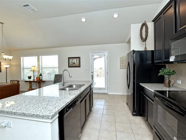 a kitchen with kitchen island granite countertop a sink refrigerator and cabinets