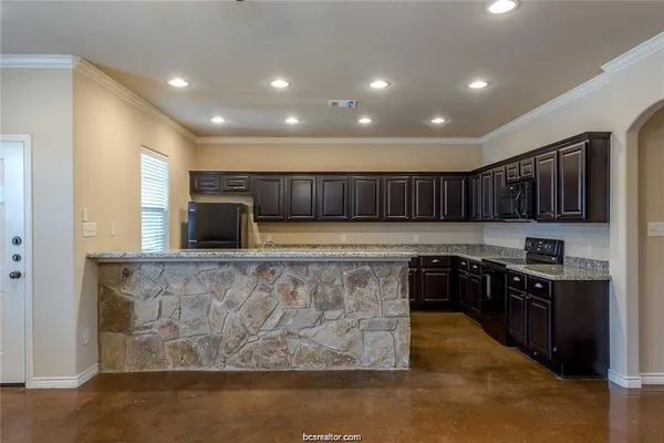 a kitchen with stainless steel appliances granite countertop a stove a sink a refrigerator a microwave a dining table and chairs
