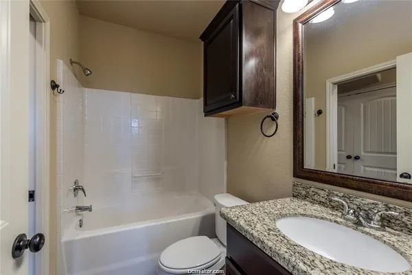 a bathroom with a granite countertop sink toilet and shower