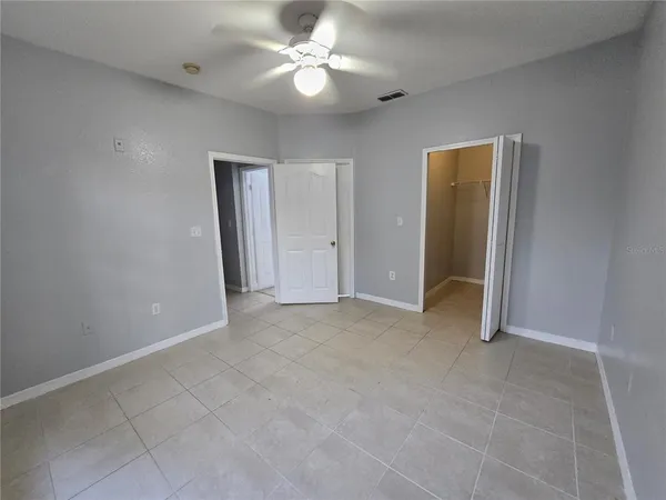 an empty room with closet and a ceiling fan
