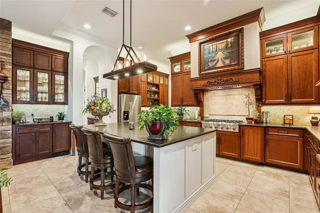 a kitchen with stainless steel appliances kitchen island granite countertop a refrigerator a stove and a wooden cabinets