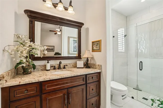 a bathroom with a granite countertop sink a toilet a mirror and shower