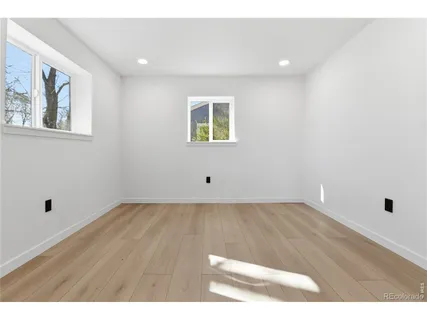 a view of an empty room with wooden floor and window