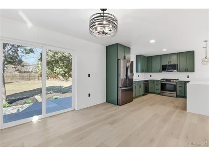 a view of kitchen with stainless steel appliances granite countertop a stove top oven a refrigerator with the island and wooden floor