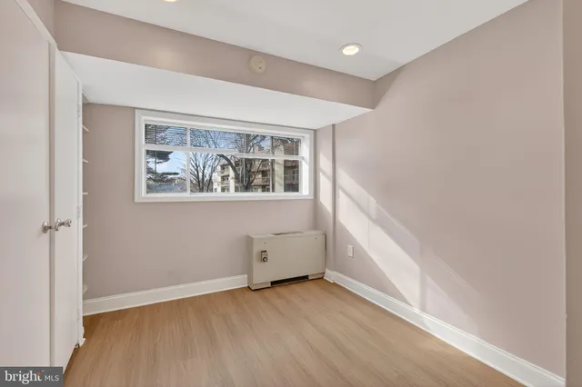 an empty room with wooden floor and window