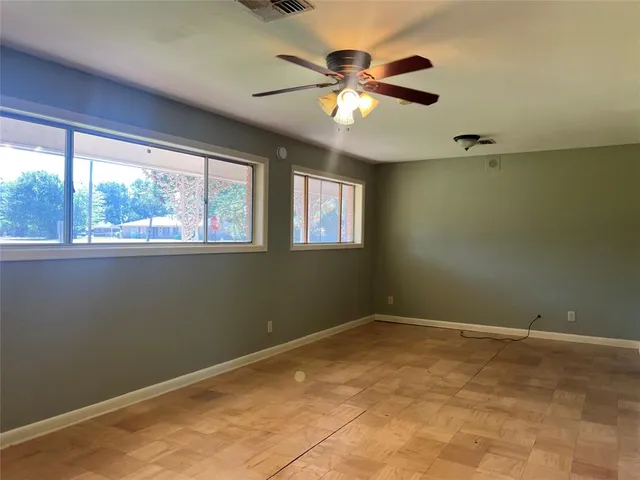an empty room with windows and fan
