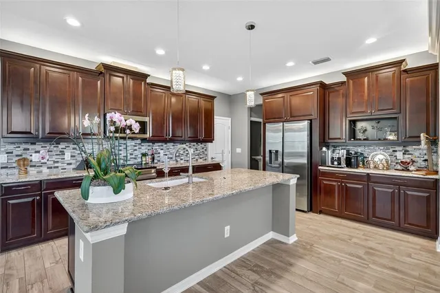 a kitchen with kitchen island granite countertop a sink counter top space appliances and cabinets