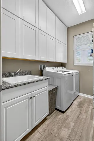 a utility room with stainless steel appliances granite countertop a sink and a white cabinets