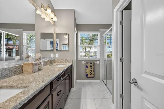 a bathroom with a granite countertop sink a mirror and a shower
