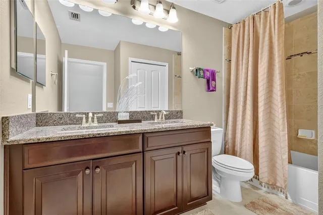 a bathroom with a granite countertop sink a toilet and a mirror