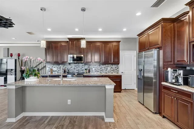 a kitchen with stainless steel appliances granite countertop wooden cabinets a refrigerator and a sink