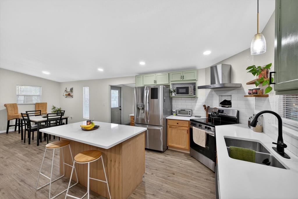 4233 Vinson Road Lakeland, FL 33810 - Photo 11 of 38 a kitchen with stainless steel appliances granite countertop a sink a stove and chairs with wooden floor