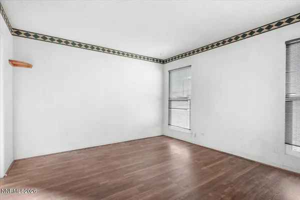a view of an empty room with wooden floor and a window