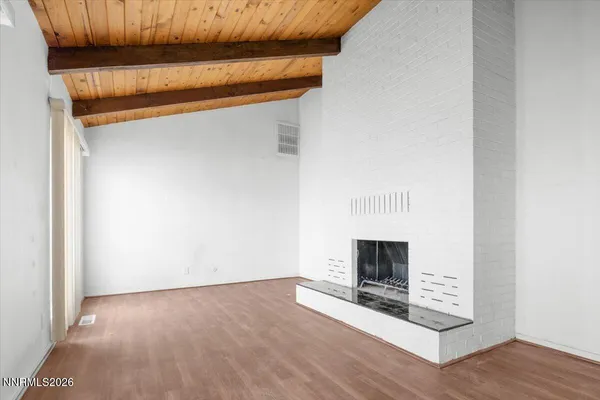 a view of a livingroom with wooden floor and a fireplace