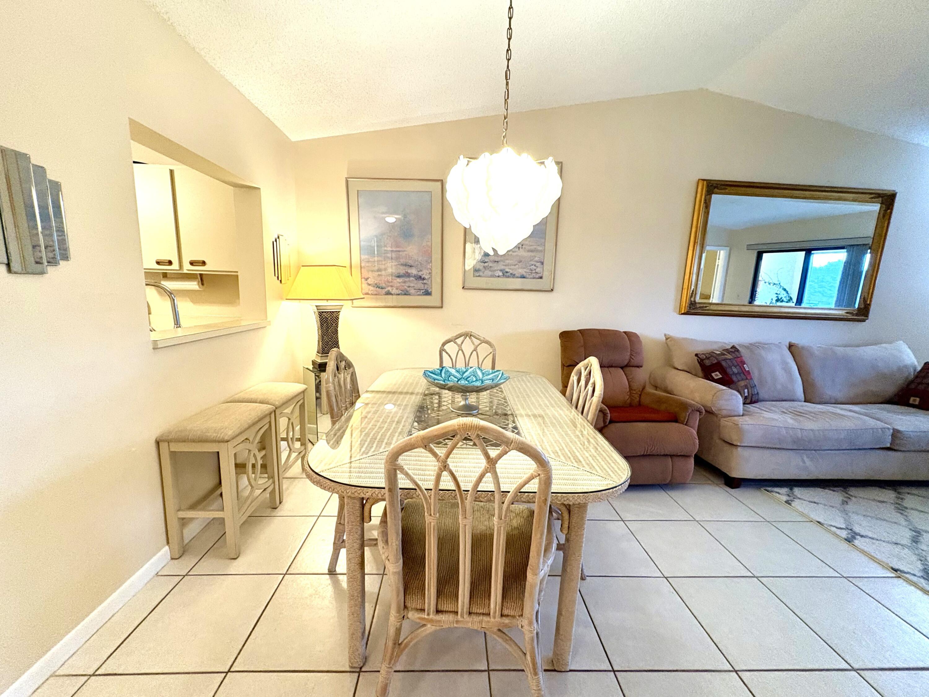 9485 Boca Cove Circle, Unit 709 Boca Raton, FL 33428 - Photo 18 of 42 a living room with furniture and a chandelier