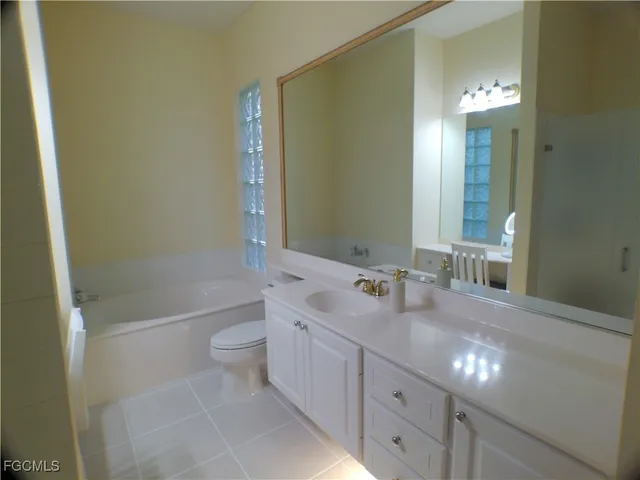 a spacious bathroom with a granite countertop sink a toilet and a mirror