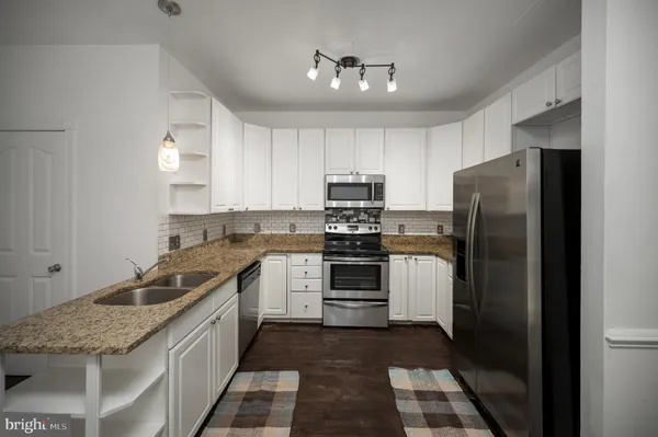 a kitchen with granite countertop a stove sink and cabinets