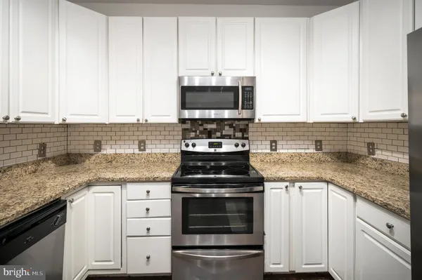 a kitchen with granite countertop a sink and a white cabinets