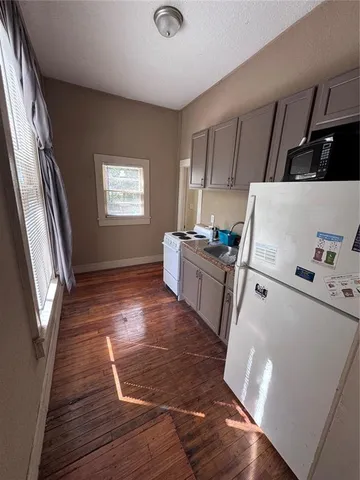 a room with wooden floors and white appliances
