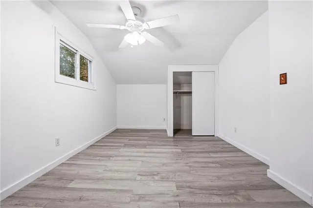 an empty room with wooden floor chandelier fan and windows