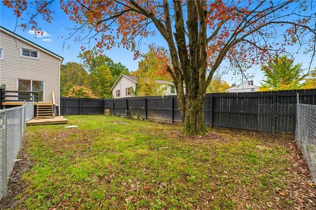 a view of backyard with wooden fence and large trees
