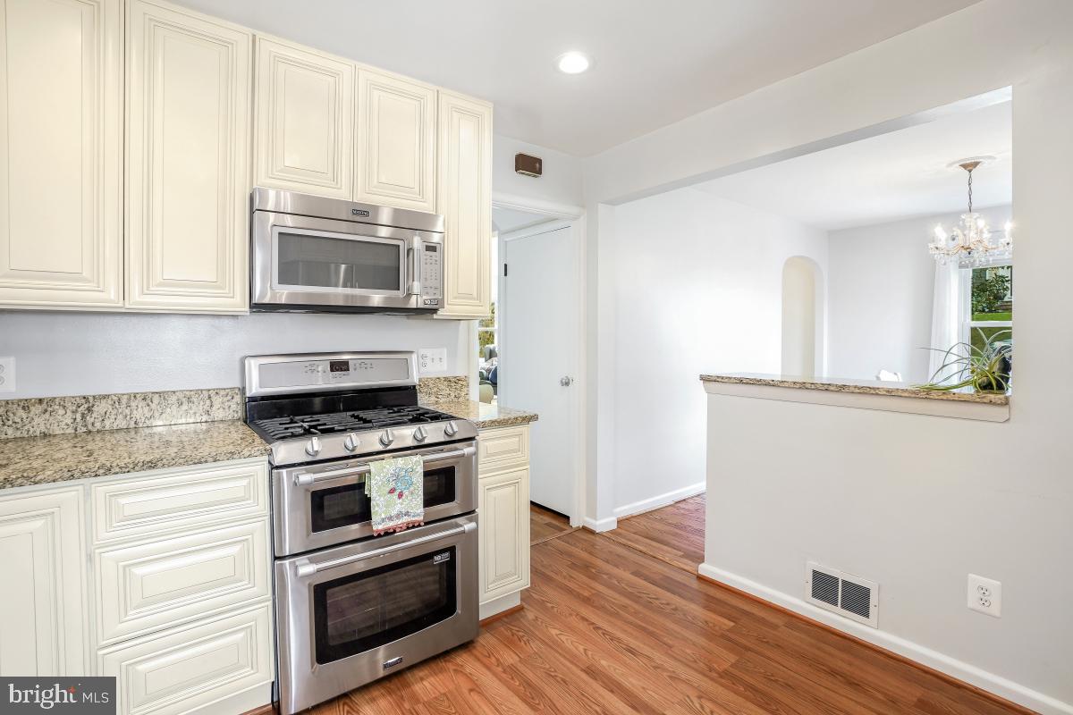 6013 Hawthorne Street Cheverly, MD 20785 - Photo 14 of 30 a kitchen with granite countertop wooden cabinets and stainless steel appliances